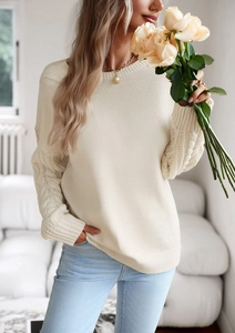 Dettaglio della trama a treccia sulle maniche di un maglione girocollo beige da donna