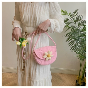 Detailed shot of pink woven straw saddle bag featuring a large white daisy flower decoration