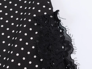 Detailed close-up of black fabric with white polka dots and elegant lace trim stitching