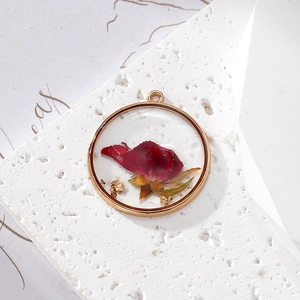 Detailed macro view of a round resin pendant with a red dried rose and gold foil flakes