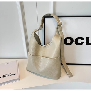 Détail du sac hobo en cuir beige à motif litchi avec large bandoulière et poches