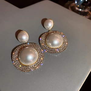 Vue détaillée de boucles d'oreilles dorées vintage avec perles étagées et strass brillants