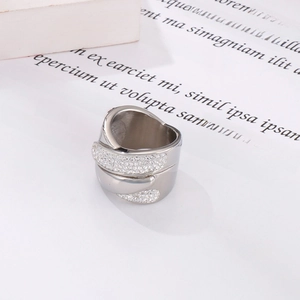 Macro view of a silver crossover ring featuring a wide band with micro-pave rhinestones