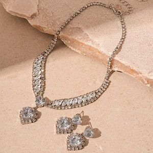 Macro detail of silver tone heart pendant and drop earrings with cubic zirconia stones