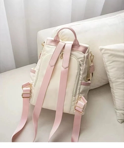 Close-up of beige Oxford backpack with pink straps and premium gold metal zippers