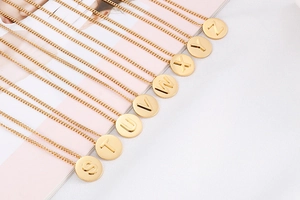 Macro detail of gold initial letter pendants S-Z with embossed relief on link chains