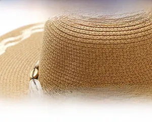 Detail of papyrus straw hat featuring woven texture and shell decorative band