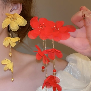 Close-up of red and yellow fabric flower earrings with long beaded fringe tassels