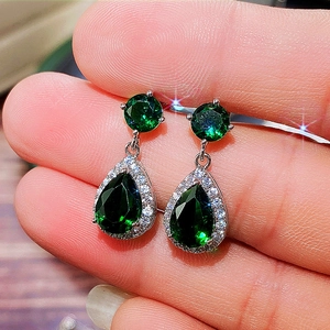 Close-up of elegant teardrop emerald green earrings with halo cubic zirconia stones