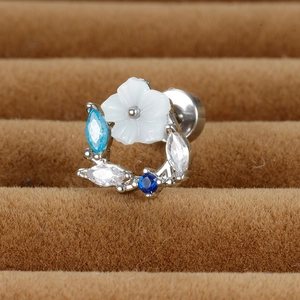 Vue macro de boucles d'oreilles fleur avec gemmes bleues et blanches sur support velours