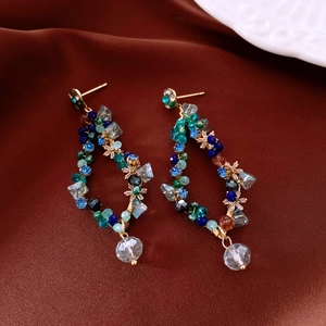 Macro detail of beaded tassel earrings with crystal drops on a satin background