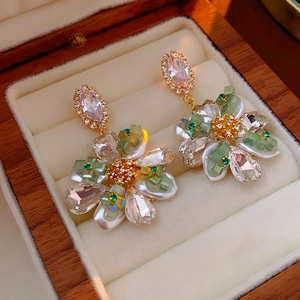 Détail de boucles d'oreilles fleur avec strass et perles sur une boîte en bois