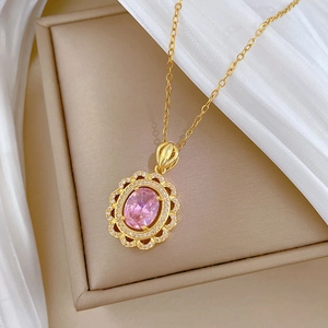 Gros plan d'un collier doré avec une pierre ovale rose entourée de cristaux