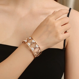 Close-up of rose gold tree of life bangle featuring sparkling white rhinestones and heart motif