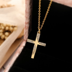 Macro detail of gold cross pendant with cubic zirconia inlay in a premium jewelry box