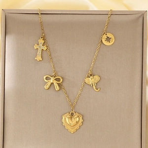 Close-up of gold titanium necklace featuring bow, cross, elephant, and heart pendants
