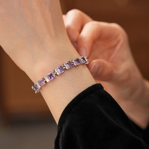 Detalle macro de pulsera plateada con circón morado cuadrado y detalles brillantes