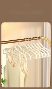 Detail of cream flocked clothes hangers with non-slip shoulder notches on a metal rod