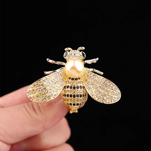 Detail of bee brooch in gold finish with sparkling crystals and a central pearl