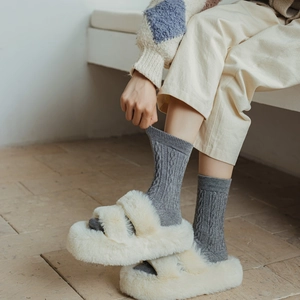 Détail de chaussettes en maille torsadée grise avec des pantoufles blanches à plateforme