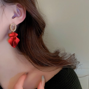 Close-up of vintage red petal drop earrings with textured gold ring on a model
