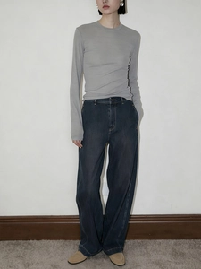 Detail of grey slim knit long sleeve top with textured bamboo-like fabric and denim
