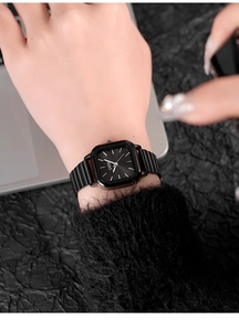 Minimalist black square dial watch with bamboo steel strap worn on a female wrist