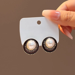 Close-up of vintage-style pearl earrings with gold hollowed-out texture on a card