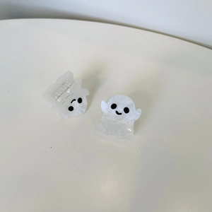 Detail of small white marble ghost hair claws with cute faces in minimalist setting