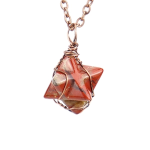 Macro shot of hand-wrapped red jasper merkaba star pendant with antique bronze wire detail