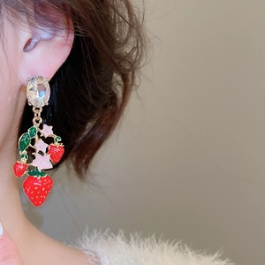 Detail of strawberry drop earrings with red enamel and crystals worn by a model