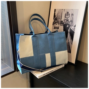 Detailed texture of a large color-block denim tote bag with durable canvas stitching