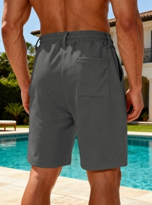 Detailed back view of dark grey quick-dry beach shorts with rear pocket in outdoor setting