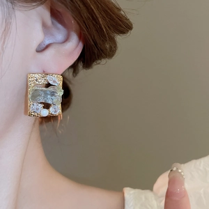 Detail of vintage square gold-plated earring with green stone, zircon and pearl accents