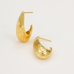 Close-up of golden teardrop earrings featuring a refined vertical brushed metal texture