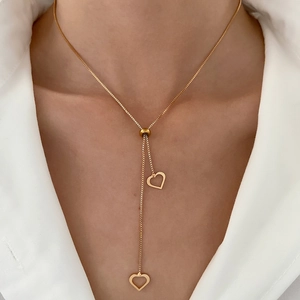 Close-up of golden heart lariat necklace with adjustable sliding bead on white shirt