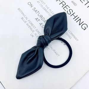 Sweet black faux leather bow hair tie accessory on a decorative typography background