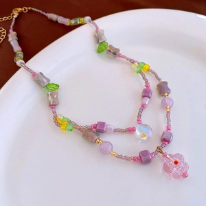 Detail of beaded double-layer necklace with flower pendant in a white ceramic plate