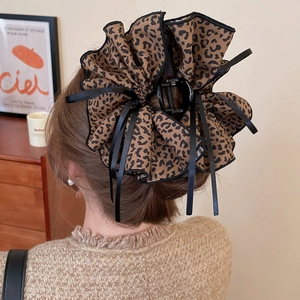Detail of leopard print fabric hair claw with layered lace edges in a warm retro style