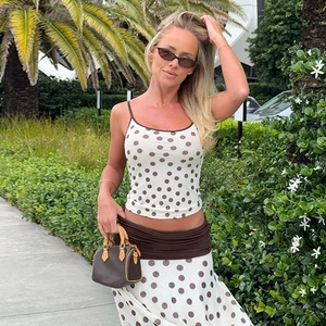 Photo en extérieur d'une femme en ensemble crop top à pois et jupe midi chic