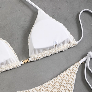 Detailed macro view of white crochet lace bikini with gold buckle and removable padding