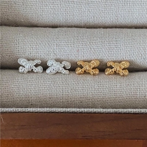 Macro shot of 925 silver bow stud earrings with intricate woven texture in gold and silver