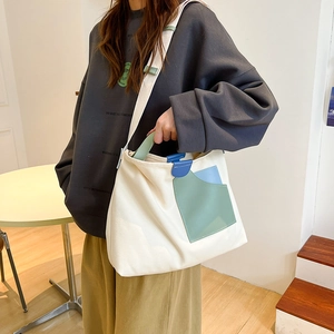 Detail of canvas tote bag featuring green and blue geometric patch pockets with shoulder strap