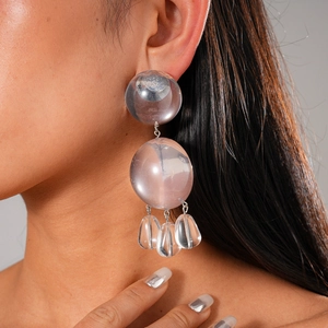 Boucles d'oreilles pendantes en résine rose transparente sur un modèle féminin