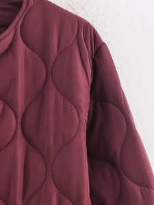 Detail of burgundy quilted jacket showing high-quality stitching and fabric texture