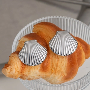 Minimalist stainless steel shell stud earrings in silver finish on a croissant display