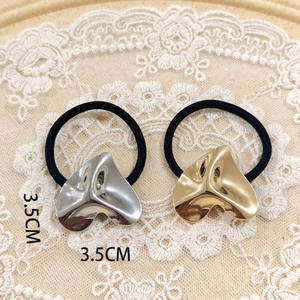 Close-up of 3.5cm gold and silver heart-shaped metal hair ties on elegant lace