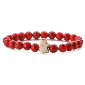 Close-up of beaded elephant bracelet with red textured beads and a white elephant charm