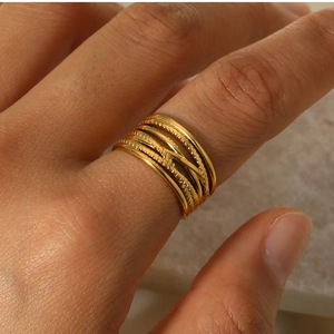 Macro shot of 18k gold irregular woven texture ring on hand with warm stone background