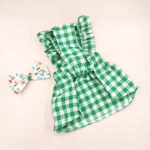 Detail of green plaid Christmas dog dress featuring pleated ruffles and floral bow accessory